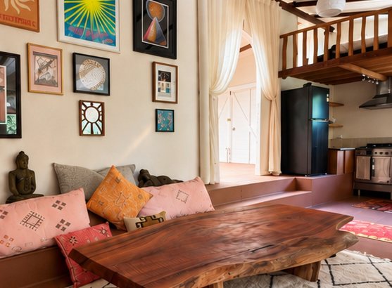 Inside the Dojo: a timber slab low table, cushions along the wall, framed prints and a mezzanine above